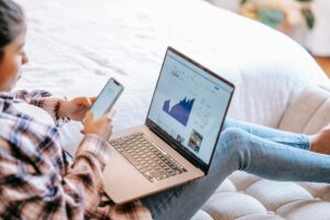 girl using her phone and laptop on her lap